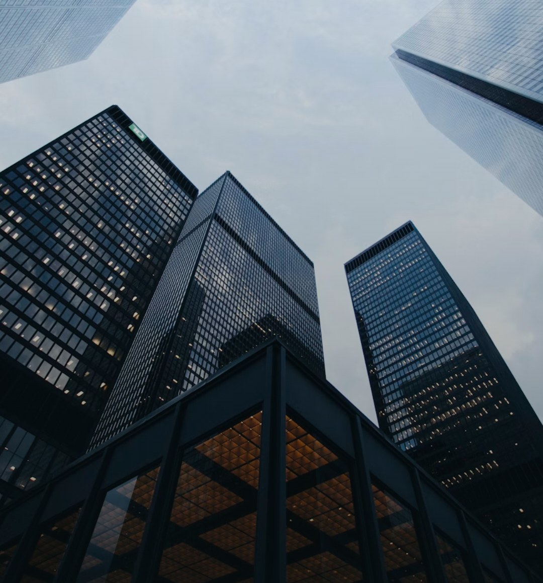 Glass towers rising into an overcast sky, seen from street level